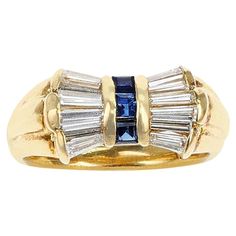 A stunning and elegant 0.81 ct. Diamond Baguettes and 0.28 cts. Square Cut Blue Sapphire Bow Ring made in 18 Karat Yellow Gold. The ring size is US 6.25. Luxury Yellow Gold Baguette Cut Sapphire Ring, Luxury Yellow Gold Rectangular Sapphire Ring, Luxury 14k Gold Baguette Cut Sapphire Ring, 14k Gold Baguette Cut Blue Sapphire Ring, 14k Gold Baguette Cut Sapphire Ring, Luxury Baguette-cut Sapphire Ring With Diamond, Bow Ring, Square Cut, The Ring