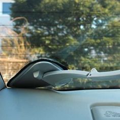 a car dashboard with the sunroofer partially open and trees in the background