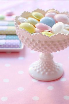 there is a small glass bowl filled with candies on the table next to a cell phone