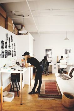 a person standing at a desk in a room with lots of pictures on the wall