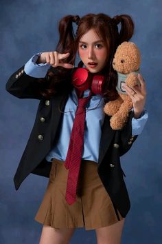 a young woman holding a teddy bear and wearing a skirt with her hair in pigtails