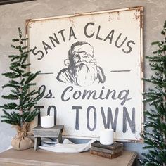 there is a sign that says santa claus coming to town on the wall next to some christmas trees