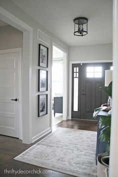 an entryway with pictures on the wall and a rug in front of it,