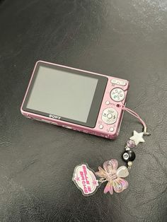 a pink digital camera sitting on top of a table next to a keychain