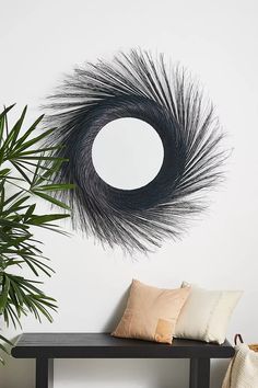 a black bench sitting under a mirror next to a potted palm tree in front of a white wall