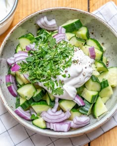 a bowl filled with cucumbers, onions and sour cream