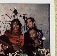 a group of people sitting next to each other in front of a wall with graffiti on it