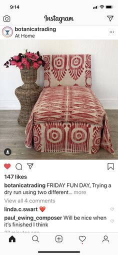 a bed with red and white bedspread next to a vase filled with flowers