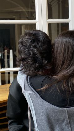 two people sitting at a table with their backs to each other