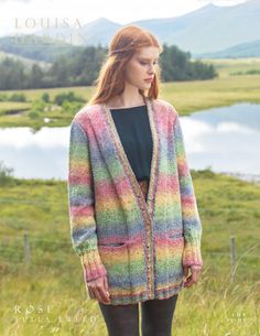 a woman standing in the grass wearing a colorful cardigan