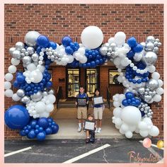 two people standing under an arch made out of balloons