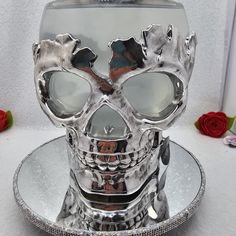 a silver skull sitting on top of a glass plate