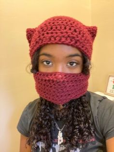 a woman wearing a red knitted cat hat and scarf over her face with the hood pulled back