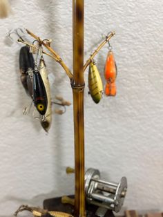 several fishing hooks hang on a wooden pole in front of a wall with other items