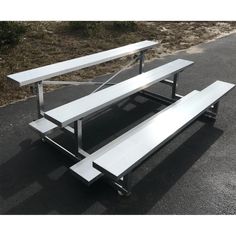 two white benches sitting on top of a parking lot