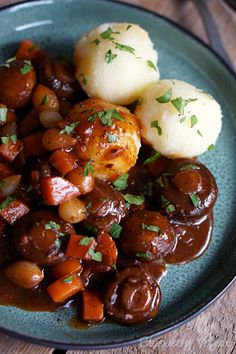 a blue plate topped with meat, potatoes and gravy on top of a wooden table