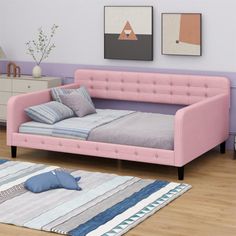 a pink daybed sitting on top of a hard wood floor next to a dresser