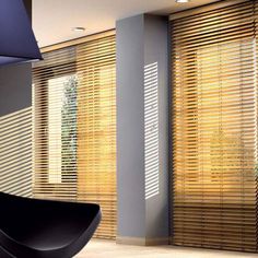 a modern living room with wooden blinds in the window sill and black chair next to it