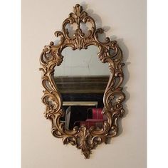 an ornate gold framed mirror hanging on the wall