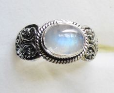 Rainbow Moonstone New with tag. Very pretty ring in size 7.75.  The stone is genuine rainbow moonstone from Sri Lanka, and the setting is genuine sterling silver, stamped 925. The rainbow moonstone has nice flashes of blue and turquoise.  All of the photos in this listing were taken in natural daylight, in my livingroom - no artificial light was used.  The stone is a 6.5X8.5mm oval cabochon cut, and it weighs 2.21cts.  As with many rainbow moonstones, this stone does have some inclusions.  The sterling silver setting is decorated with beautiful swirls of sterling silver.  This pretty ring has sterling silver under-gallery. Subjecting precious metals, pearls or gemstones to harsh chemicals and high temperatures can be damaging. My ebay store is located in the United States. International bu Pretty Ring, Artificial Light, Rainbow Moonstone Ring, Pretty Rings, Moonstone Ring, Moon Stone, Oval Cabochon, Ring Size 7, Rainbow Moonstone