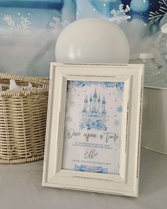 a white frame sitting on top of a table next to a basket filled with balloons