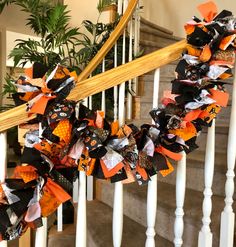 a halloween wreath on the banisters of a staircase decorated with black, orange and white fabric