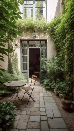 an outdoor patio with tables and chairs surrounded by greenery on either side of the door