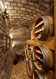 several wine barrels are stacked on the wall in an old brick cellar with tile flooring