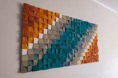 a wall hanging made out of different colored wood blocks on a white wall next to a window