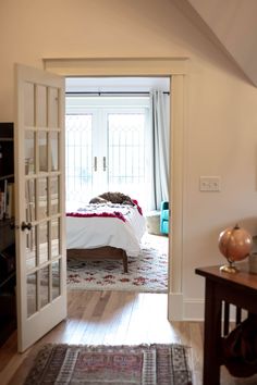 an open door leading to a bedroom with a bed in the corner and a rug on the floor