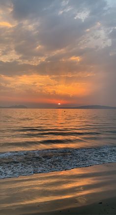 the sun is setting over the ocean with clouds in the sky and water on the beach