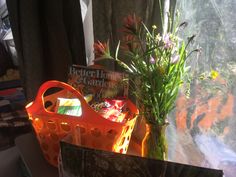 some flowers are sitting in a basket on a window sill next to a sign