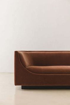 a brown couch sitting on top of a white floor next to a lamp and wall