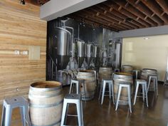 there are many barrels in the room with stools and tables next to each other