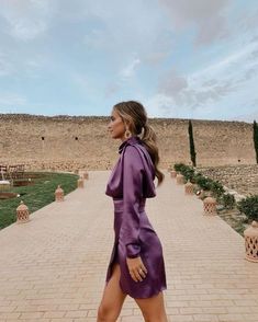 a woman in a purple dress walking down a brick walkway