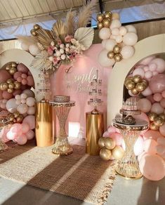 a table topped with balloons and vases filled with pink, gold and white flowers