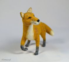 an orange and white toy fox standing on its hind legs in front of a gray background