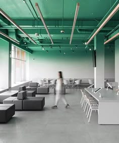 a person walking in an empty office with green walls and white furniture on the floor