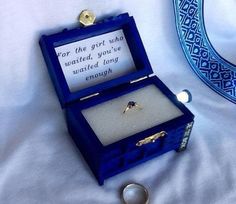 an open blue box with a ring in it on a white sheet and the words i want to be proposed to like this school of magic