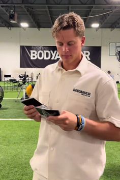 a man in a white shirt is looking at something on a clipboard while holding a yellow ball