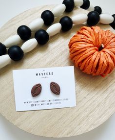 an orange and black beaded necklace next to a pair of earrings on a wooden board