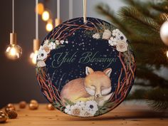 a christmas ornament with an image of a sleeping fox and flowers on it