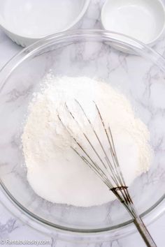 flour and whisk in a glass bowl on a marble counter