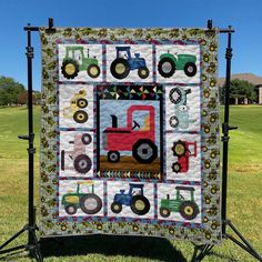 a quilted wall hanging with tractors and farm vehicles on it in the grass near a field