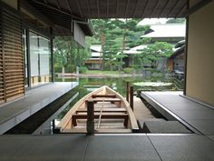 a small boat is docked in the water near a building with large windows that look out onto a lake