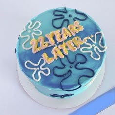 a blue cake with writing on it sitting next to a pair of scissors and a knife