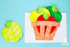 an apple and carrot cut out of paper on a blue background with two pieces of paper