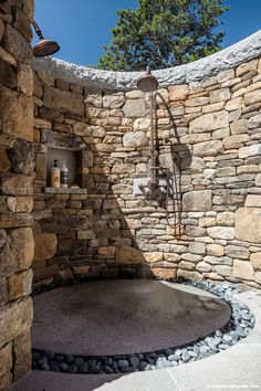 an outdoor shower with stone walls and rock flooring is shown in this image, there are