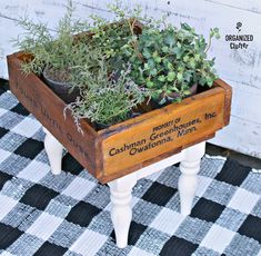 an old wooden box filled with plants on top of a checkered rug