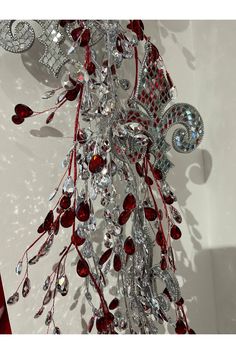 a chandelier hanging from the ceiling with red and silver decorations on it's sides